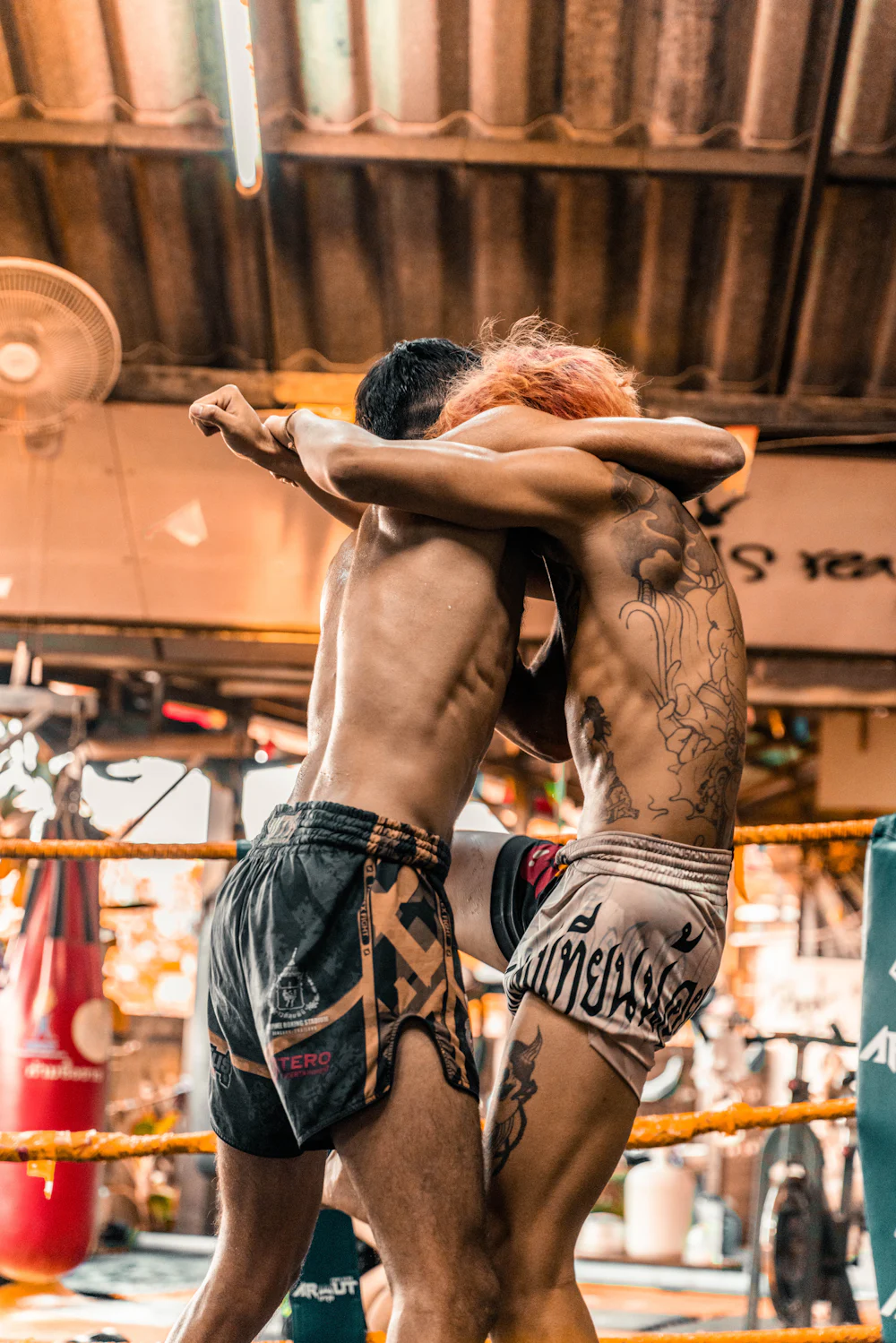 Deux boxeurs thaïs en corps-à-corps sur un ring